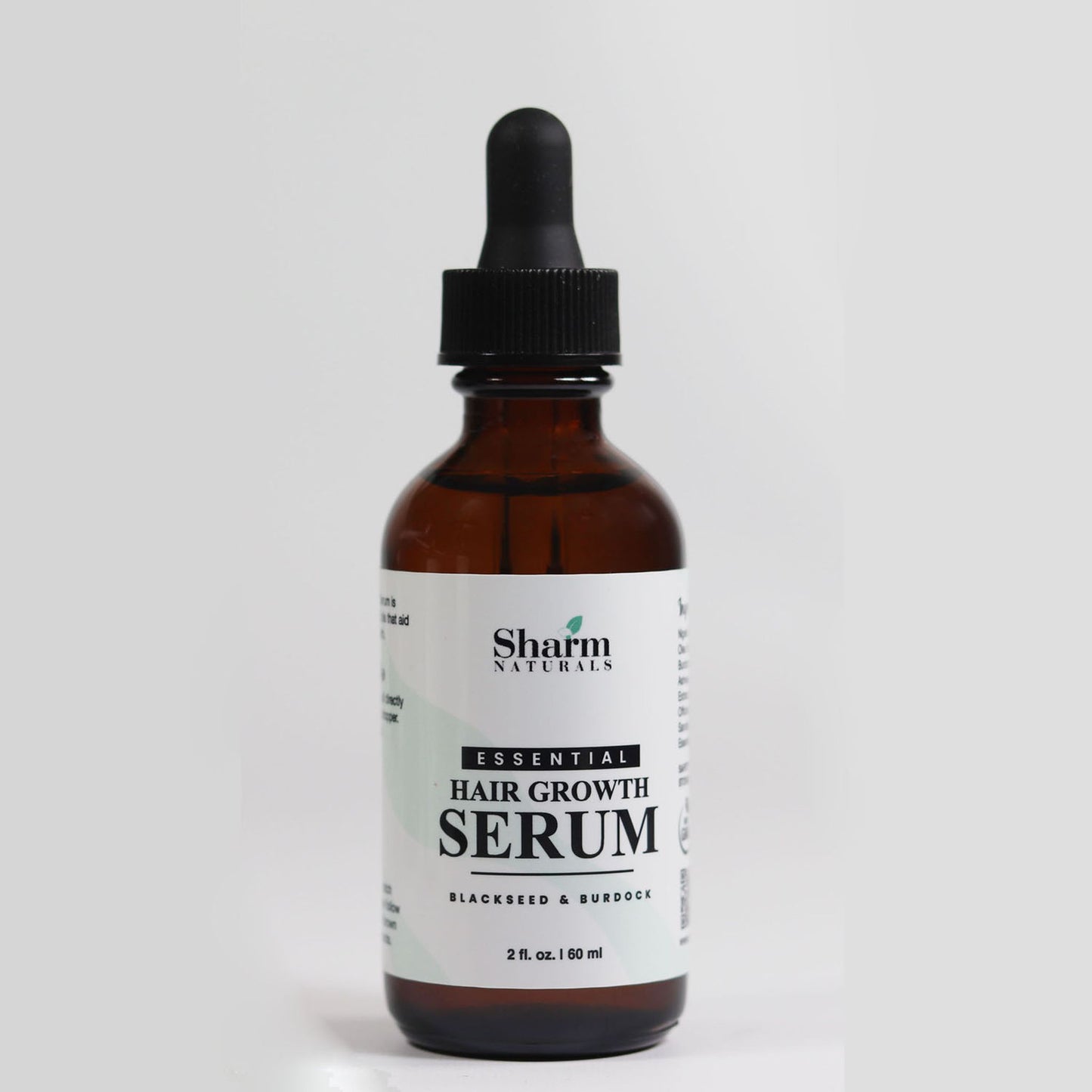 A bottle of Essential Hair Growth Serum with a dropper cap, labeled for restoring and growing hair.